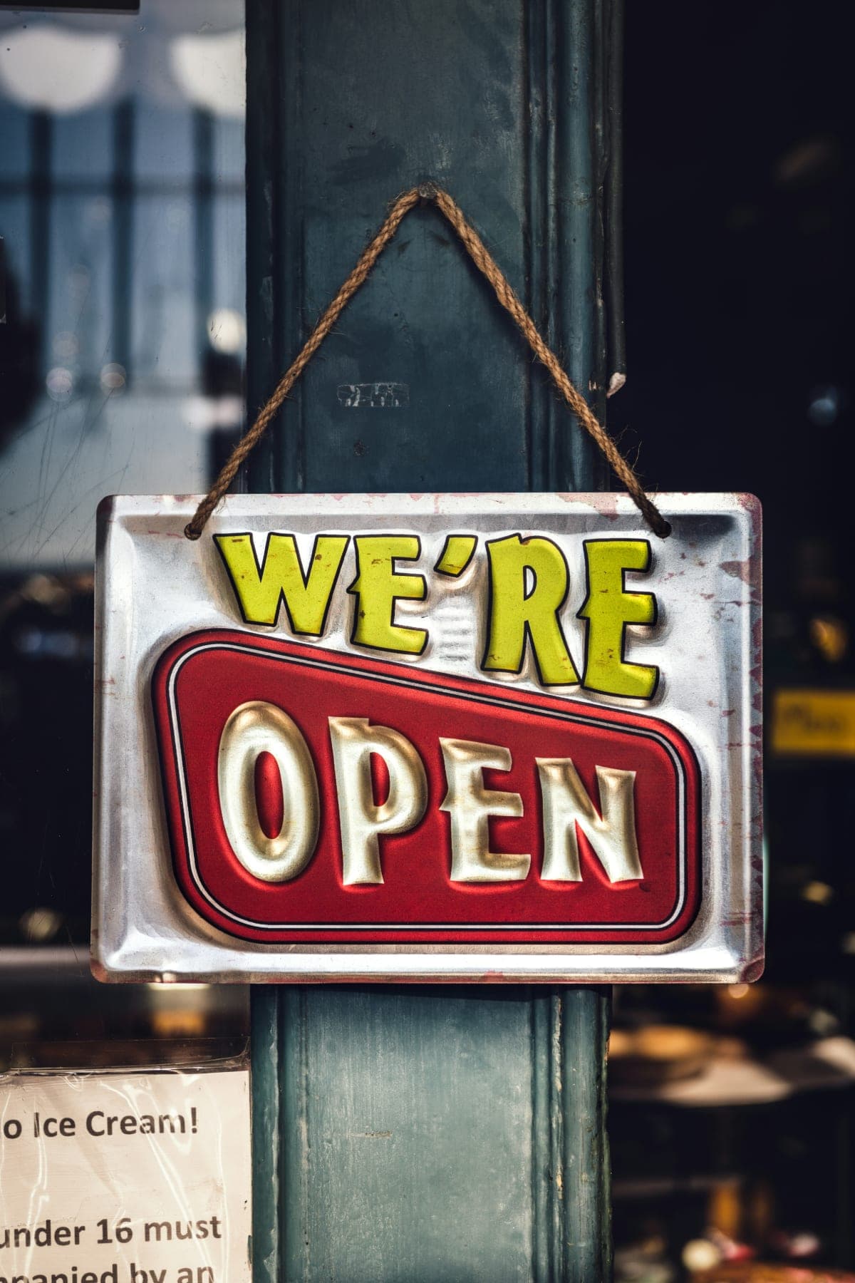 A hand-painted We're Open sign hanging in a shop door
